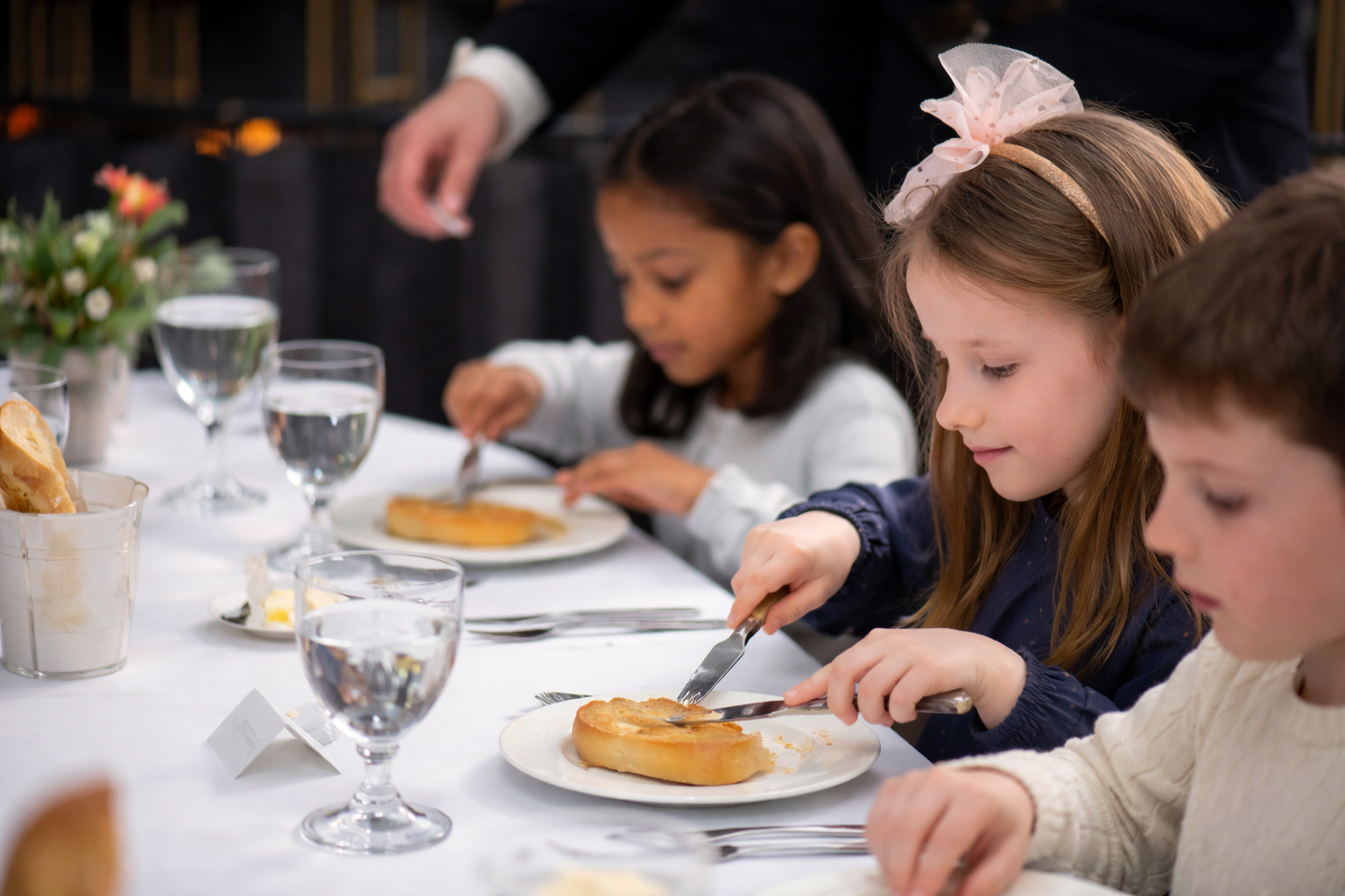 Children practicing dining etiquette at a formal table