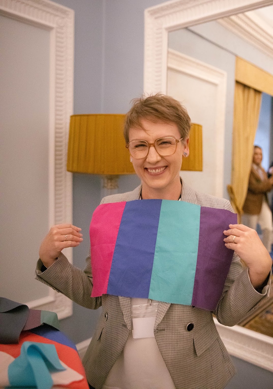 A woman holding fabric swatches against herself in a bright salon