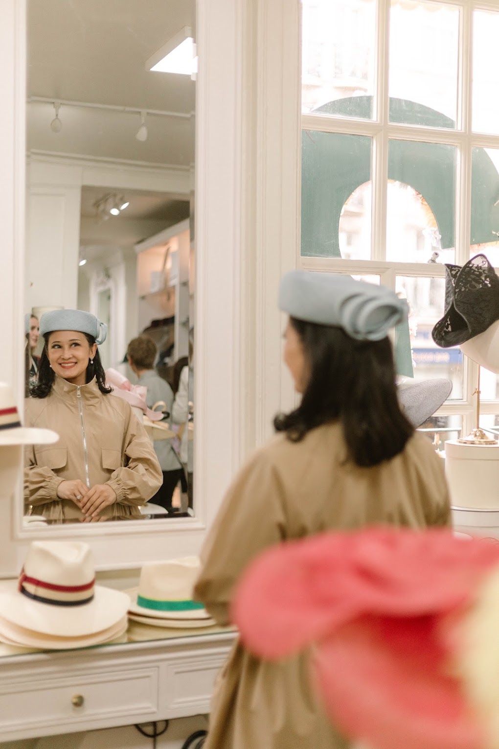 A woman trying on a pale blue hat at a mirror in a hat salon